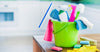 Cleaning supplies in a green bucket on a kitchen counter